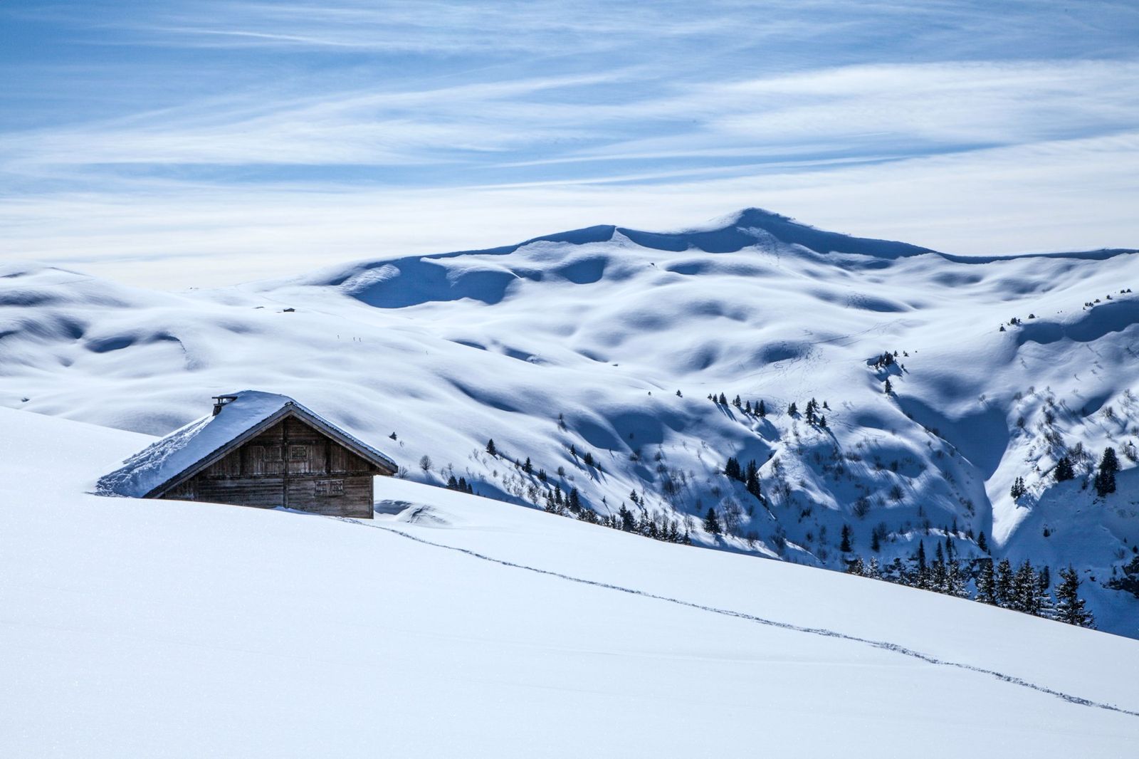 A lone alpine chalet buried in deep snow